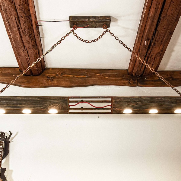 Une longue lampe en bois constituée d'une poutre suspendue à des chaînes dans un style industriel. Un lustre en bois unique avec 6 ampoules LED, fait main