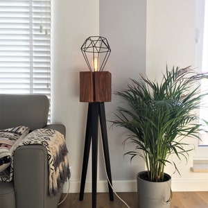 Tripod floor lamp. Wooden decorative loft lamp. Industrial tripod lamp. A floor lamp made of an old beam on black legs.