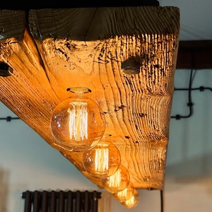 May include: A rustic wooden ceiling light fixture with five exposed filament light bulbs. The wood is a warm brown colour and has a natural, weathered finish.