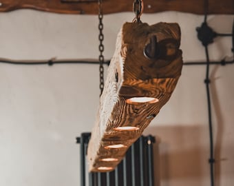 Una larga lámpara de madera de una viga colgada de cadenas en un estilo rústico. Una lámpara de madera única con 5 bombillas LED, hecha a mano.