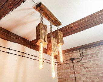 A wooden beam lamp hanging on chains in a rustic style. Triple lamp made of wood above the table, handmade. Wooden chandelier