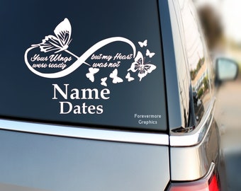 May include: White vinyl decal with an infinity symbol and butterflies. The text reads "Your Wings were ready but my Heart was not" with space for a name and dates. The decal is on a black car window.