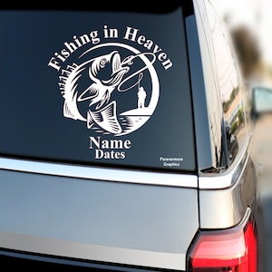 May include: White vinyl decal with a silhouette of a fish jumping out of the water with a fisherman in the background. The text "Fishing in Heaven" is in a circle around the image. The text "Name Dates" is below the circle. The text "Forevermore Graphics" is below the text "Name Dates".