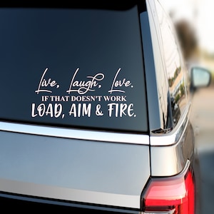 May include: White vinyl decal with the text "Live, Laugh, Love. If that doesn't work, Load, Aim & Fire." applied to a car window. The decal is in a cursive font, with the second line in a more straightforward font.