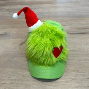 May include: Green fuzzy hat with a red heart and a red Santa hat on top.
