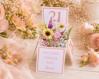 Op de afbeelding: Een pop-up wenskaart met een boeket papieren bloemen, waaronder een zonnebloem, rozen en lavendel. De kaart heeft een witte basis met perzikkleurige randen en de tekst "Happy 21st Birthday to our beautiful daughter Jane" op het voorpaneel.