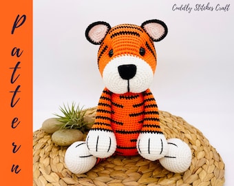 May include: A crocheted tiger stuffed animal with orange and black stripes. The tiger has white paws and a white face with black eyes and a black nose.