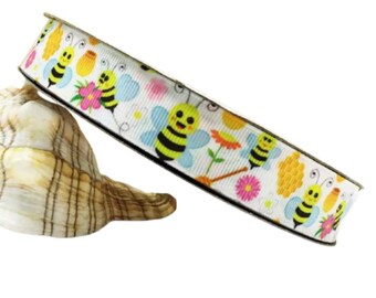 May include: White ribbon with a repeating pattern of yellow and black cartoon bees, honeycombs, and flowers.