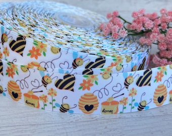 May include: White ribbon with a repeating pattern of bees, honeycombs, and hearts. The ribbon has a textured, woven look. The text "honey" appears on the ribbon.