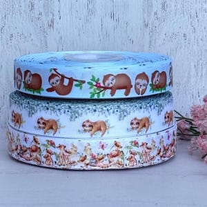 May include: Three rolls of blue and white ribbon with a sloth print. The ribbon is perfect for crafting, gift wrapping, and decorating.