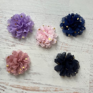 May include: Five fabric flower hair clips with gold polka dots. The flowers are in shades of purple, pink, and blue.