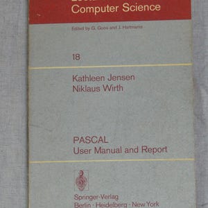May include: A softcover book titled Lecture Notes in Computer Science 18, Pascal User Manual and Report by Kathleen Jensen and Niklaus Wirth. The cover features a red top section, a grey body, and yellow horizontal lines with Springer-Verlag text.