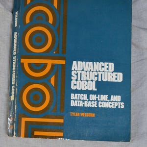 May include: A hardcover textbook titled Advanced Structured COBOL: Batch, On-Line, and Data-Base Concepts by Tyler Welburn. The cover features a blue background with large, stylized orange and dark blue circular graphic patterns and white text.