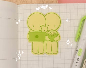 May include: A die-cut sticker featuring two pale yellow, round-headed figures in light green outlines. One figure uses a green laptop while the other reads a green book, with a small cat between them. White hand-drawn hearts and stars surround the figures.