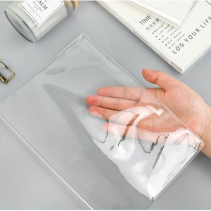 May include: Clear plastic cover for a notebook or planner. The cover is designed to protect the notebook and allow the pages to be seen through the plastic.