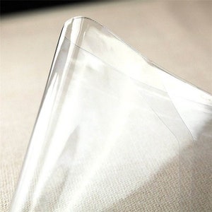 May include: A clear plastic sheet with a slight curve at the top. The sheet is smooth and transparent.