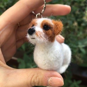 May include: A white and brown felt dog keychain with black eyes and a black nose.