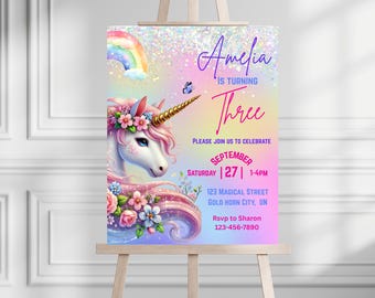 May include: A colorful invitation on an easel for Amelia's third birthday. The design features a unicorn with a floral crown, a rainbow, and the text "Amelia is turning Three." Additional text includes party details.
