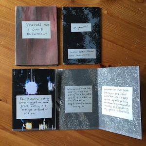 Puede incluir: Una colecci&oacute;n de cinco fanzines rectangulares con varios dise&ntilde;os de portada y etiquetas de papel blanco con texto escrito a mano. Las etiquetas incluyen frases como YOUTUBE ADS I COULD DO WITHOUT, All genuine!, y descripciones de escenas con Paul Mckenna, una dama con sombrero y una mujer en licra.