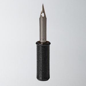 Pode incluir: Uma pena de caligrafia prateada com uma pega de plástico preto. A pena tem um pequeno furo no centro e a pega tem uma textura estriada.