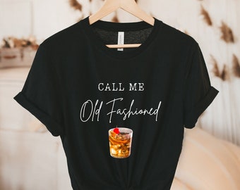 Puede incluir: Camiseta negra con el texto "Call me Old Fashioned" y un gráfico de un cóctel old fashioned con una cereza.