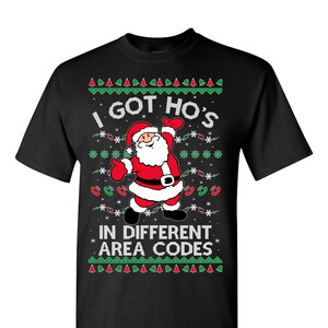 May include: Black t-shirt with a Christmas-themed design featuring Santa Claus and the text "I got ho's in different area codes".