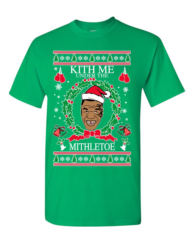 Pode incluir: Camiseta verde com um design de Natal com uma imagem de desenho animado do boxeador Mike Tyson usando um chap&eacute;u de Papai Noel e o texto "Kith Me Under The Mithletoe".