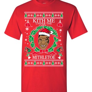 Pode incluir: Camisola vermelha de Natal com uma grinalda verde, uma imagem de um homem a usar um chap&eacute;u de Pai Natal e o texto "Kith Me Under The Mithletoe".