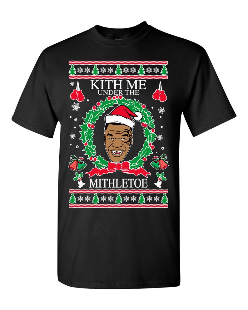Pode incluir: Camiseta preta com um design de Natal com uma imagem de desenho animado do boxeador Mike Tyson usando um chap&eacute;u de Papai Noel e o texto "Kith Me Under The Mithletoe".