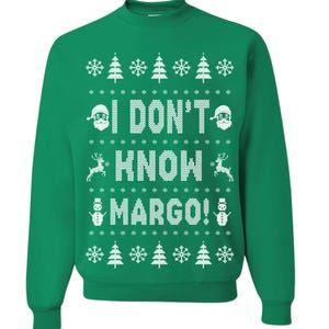 May include: Green Christmas sweater with a white knit design. The sweater features a snowman, reindeer, and Santa Claus. The text on the sweater reads "I don't know Margo!"
