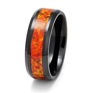 May include: A black ceramic ring with a band of orange and yellow opal inlay. The ring has a bevelled edge and a polished finish.
