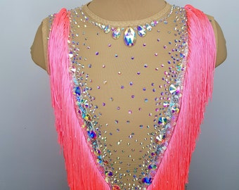 May include: A pink dance leotard with fringe trim and crystal embellishments. The leotard is made of a sheer mesh fabric and has a scoop neckline.