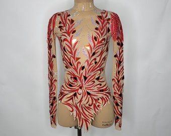 May include: A red and white leotard with a floral design and rhinestones. The leotard has long sleeves and a high neckline. The leotard is on a mannequin. The text "BOW & WOW" and "IMMINERA" is on the bottom of the leotard.