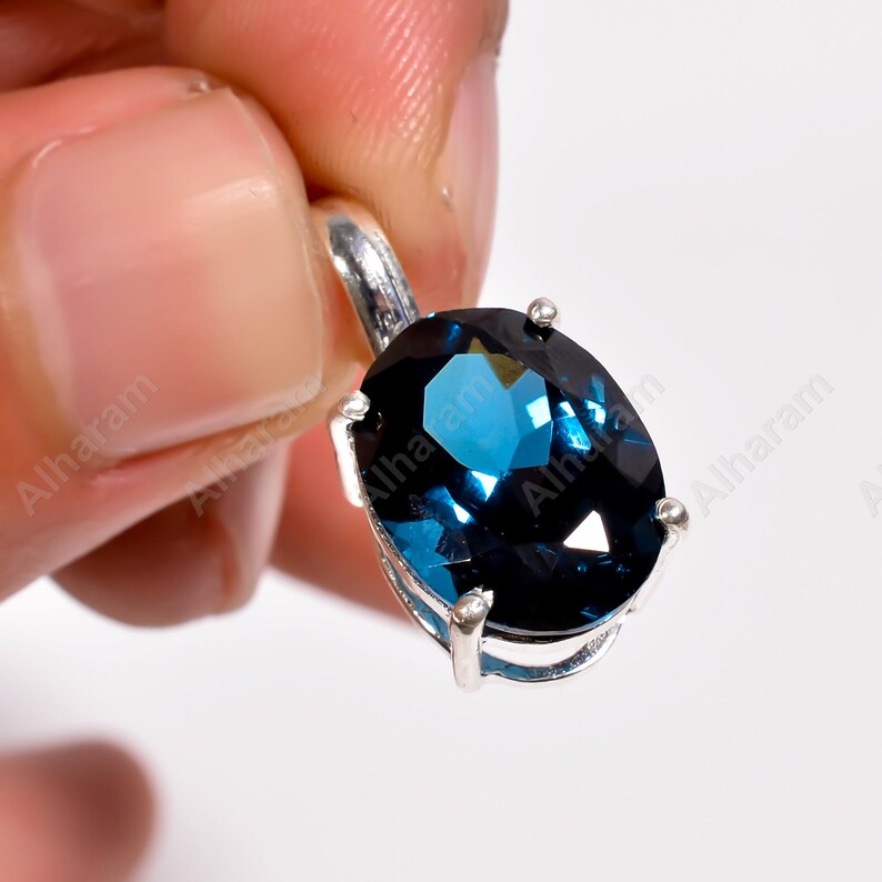 May include: A silver pendant with a large, oval-shaped, dark blue gemstone.