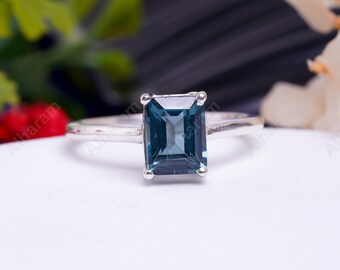 May include: A silver ring featuring a square blue gemstone.