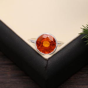 May include: A silver ring with a large, round, orange gemstone.