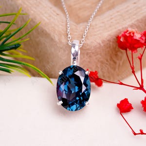 May include: A silver chain necklace with a large oval-shaped blue gemstone pendant.