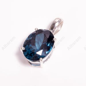 May include: A silver pendant with a large, oval-shaped, dark blue gemstone.