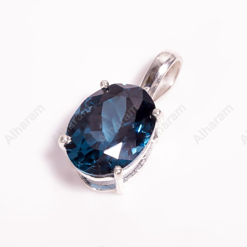 May include: A silver pendant with a large, oval-shaped, dark blue gemstone.