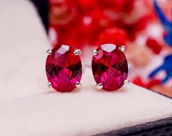 Peut inclure: Une paire de boucles d'oreilles en argent avec des pierres précieuses rouges de forme ovale.