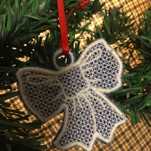 May include: A white and blue embroidered bow ornament with a red ribbon.