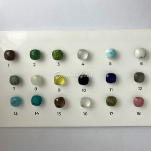 May include: A chart with 18 numbered squares, each containing a different gemstone. The gemstones are arranged in rows of six. The gemstones are various colors, including brown, green, white, blue, black, gray, turquoise, and yellow.
