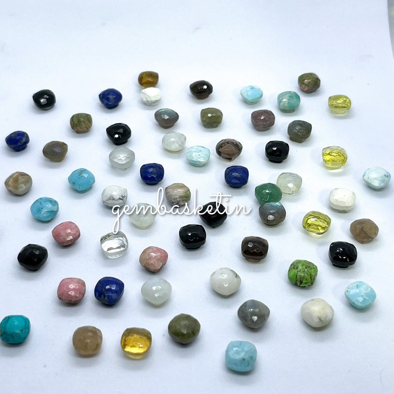 May include: Assortment of colorful gemstone beads in various shapes and sizes. The beads are arranged on a white surface.
