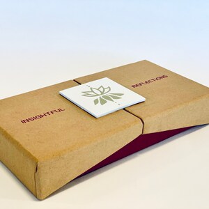 May include: A brown cardboard box with a burgundy trim. The box has a white label with a green lotus flower design and the words "INSIGHTFUL" and "REFLECTIONS" printed on it.