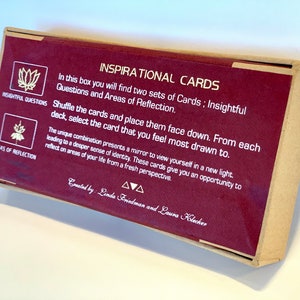 May include: A burgundy box with gold lettering that reads "Inspirational Cards". The box contains two sets of cards: Insightful Questions and Areas of Reflection. The box is designed to help you reflect on your life from a fresh perspective.