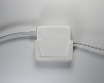 May include: A white wall charger with a white cord plugged in. The charger is mounted on a white wall mount.