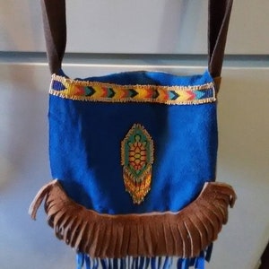 May include: A small blue suede bag with brown fringe and a beaded design of a turtle. The bag has a brown leather strap.
