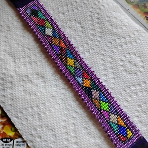 May include: A purple beaded bracelet with a colorful heart pattern. The bracelet has two snap closures.