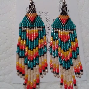 May include: A pair of turquoise, orange, yellow, white, and black beaded earrings with silver hooks. The earrings are labeled "53586 Cr #27 Lot #32".