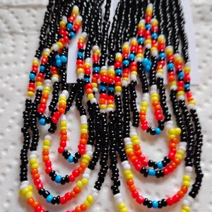 May include: Handmade beaded earrings with a vibrant design. The earrings feature black, red, yellow, orange, white, and blue beads. The top section has a triangular shape with a colorful pattern, while the lower part has multiple beaded strands.